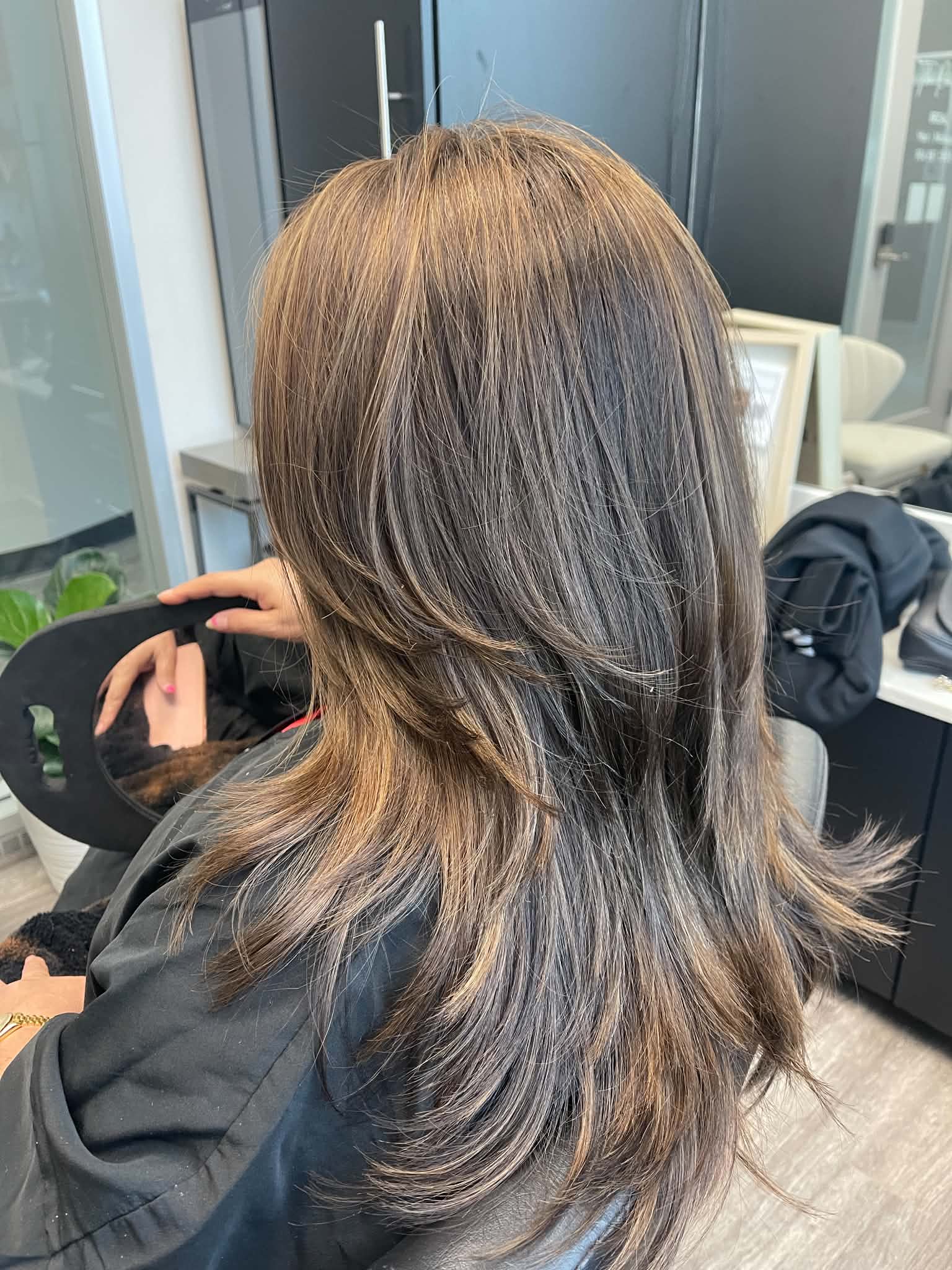 Dark brunette hair with face-framing caramel ribbons and layers
